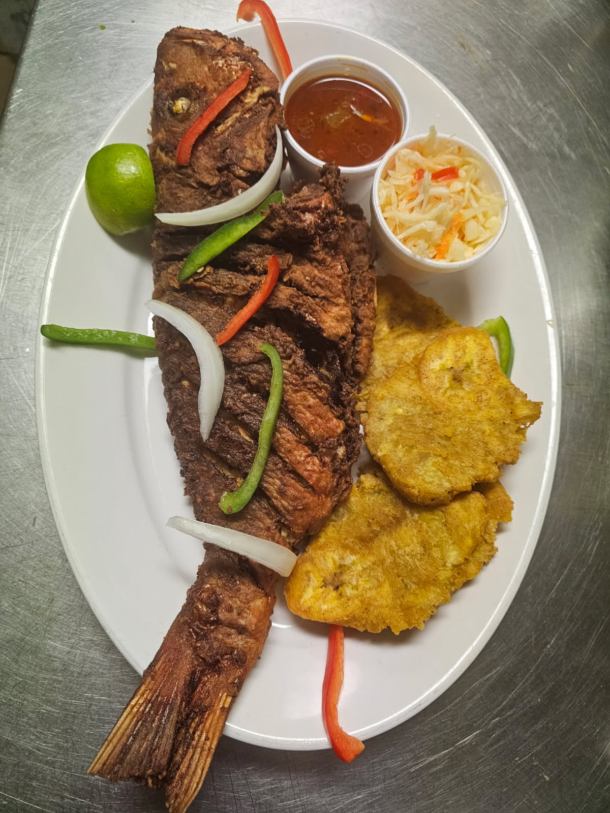 Whole fried fish with tostones, pikliz, and sauce at Klas La